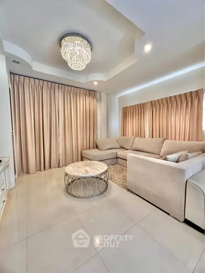 Elegant living room with plush sofa and chandelier, perfect for relaxation and entertainment.
