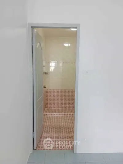 Minimalist bathroom with pink tile accents and white walls, perfect for a cozy home.