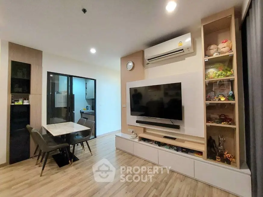 Modern living room with open layout, featuring a wall-mounted TV and stylish dining area.