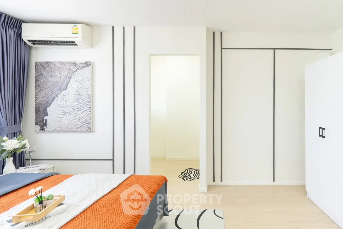 Modern bedroom with stylish decor and ample natural light, featuring a cozy bed and sleek storage solutions.