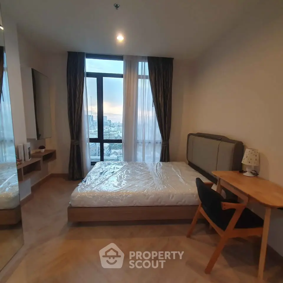 Modern bedroom with city view, featuring a cozy bed and stylish wooden furniture.