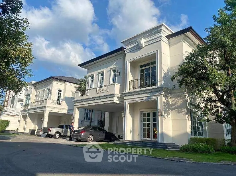 Elegant two-story white house with lush garden and driveway