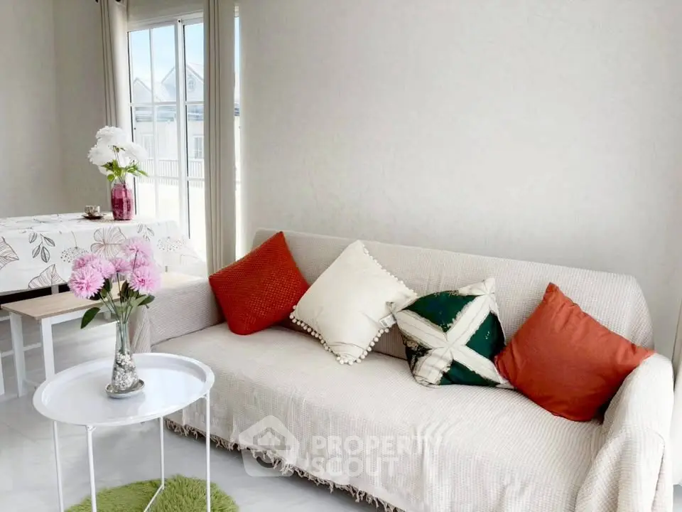 Bright living room with cozy sofa and floral decor, perfect for relaxation.