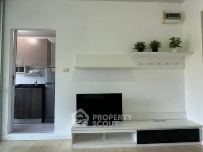 Modern living room with sleek TV stand and view into contemporary kitchen.