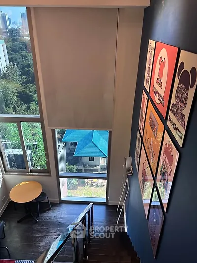 Stylish duplex interior with large windows and vibrant wall art, offering a stunning city view.