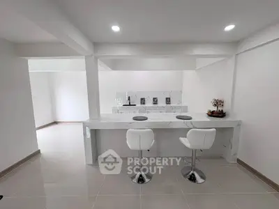 Modern kitchen with sleek marble countertops and stylish bar stools in a contemporary open layout.