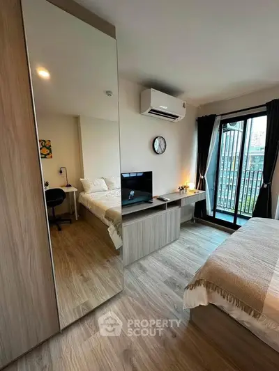 Modern bedroom with stylish decor, featuring a large mirror, cozy bed, and balcony access for natural light.