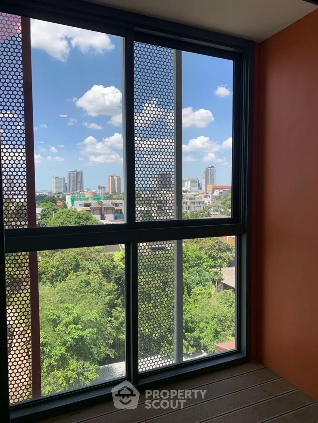 Stunning cityscape view from modern apartment balcony with lush greenery.