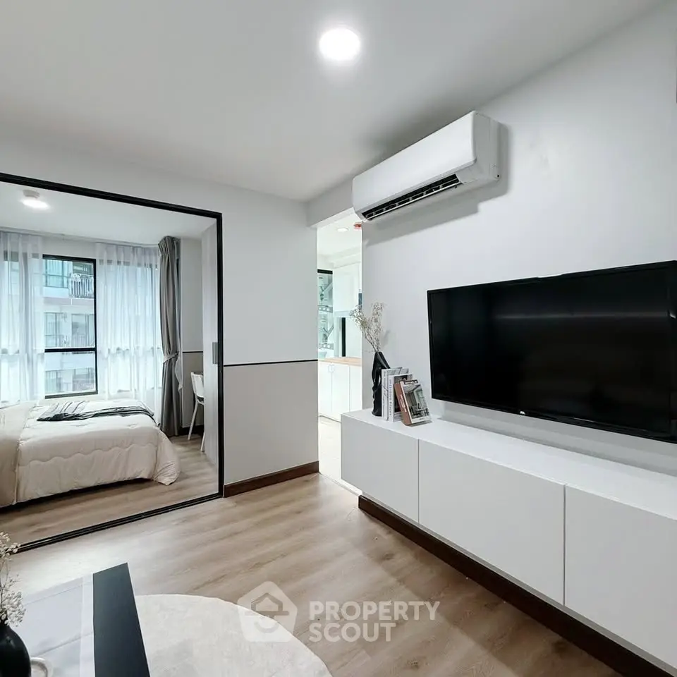 Modern living room with sleek TV unit and view into cozy bedroom