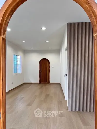Spacious modern living room with elegant wooden accents and bright natural lighting.