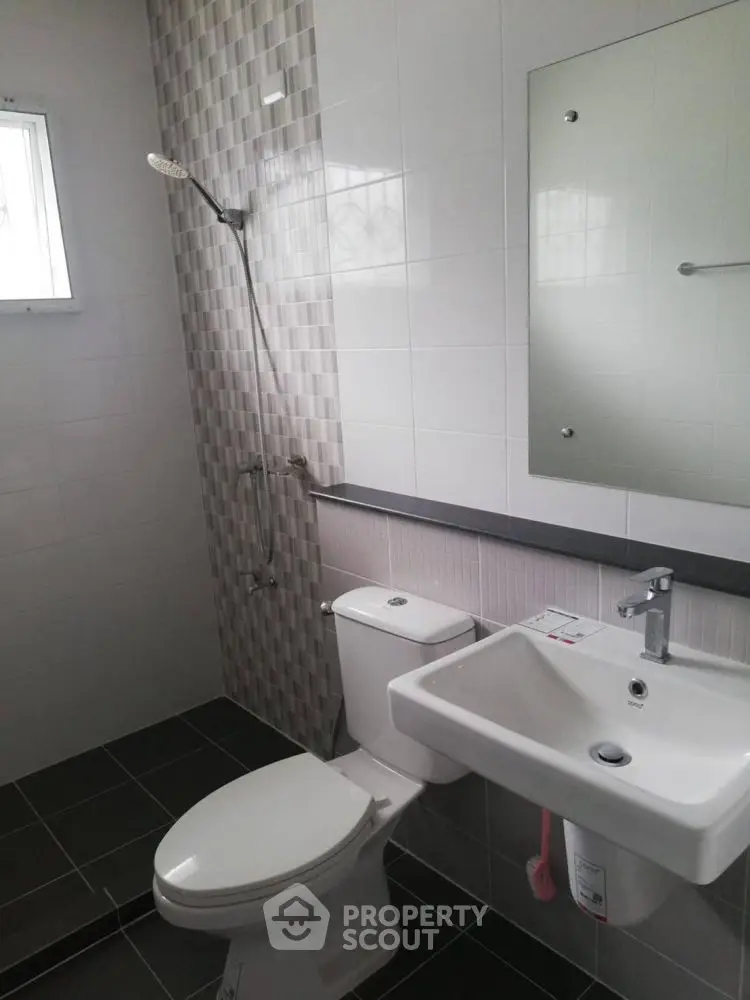 Modern bathroom with sleek fixtures and tiled walls, featuring a shower and white porcelain sink.