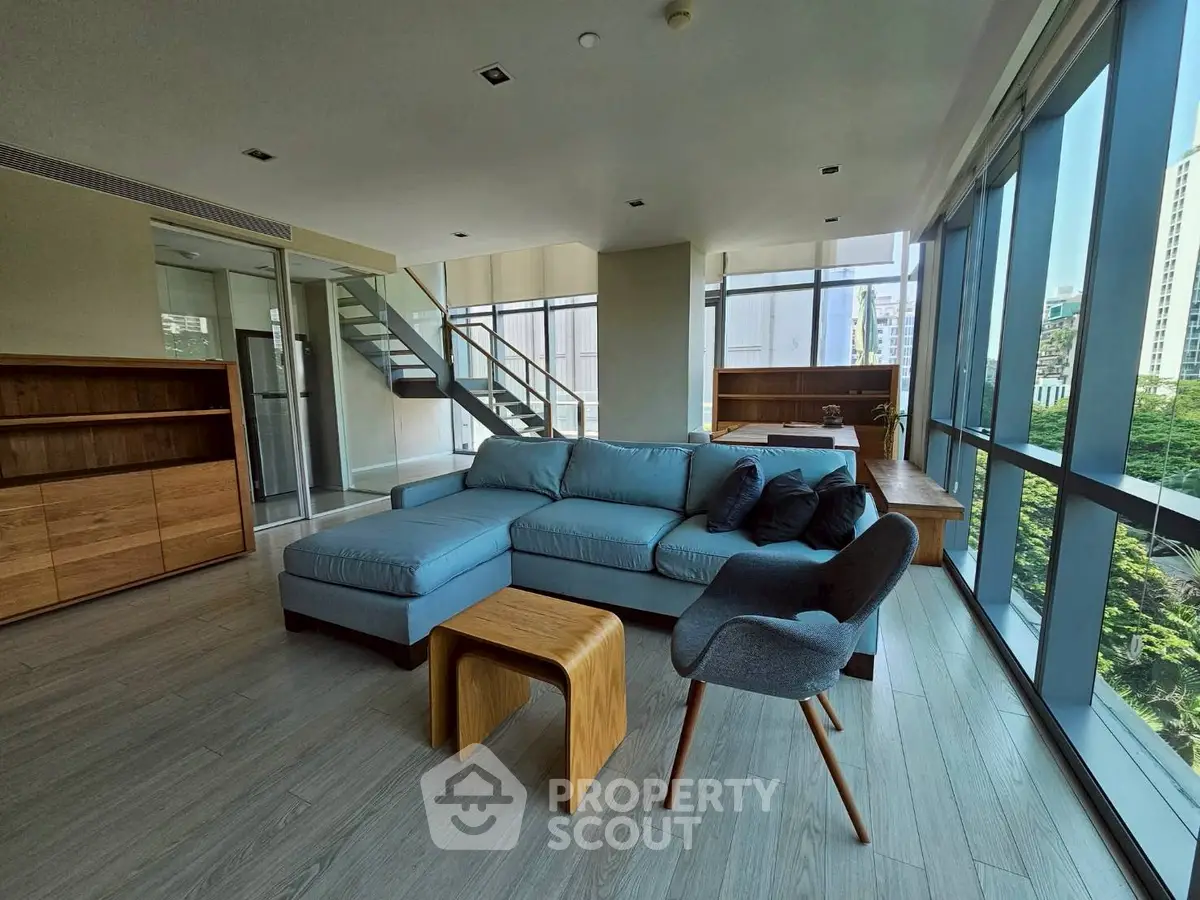 Spacious modern living room with large windows and stylish furniture in a high-rise apartment.