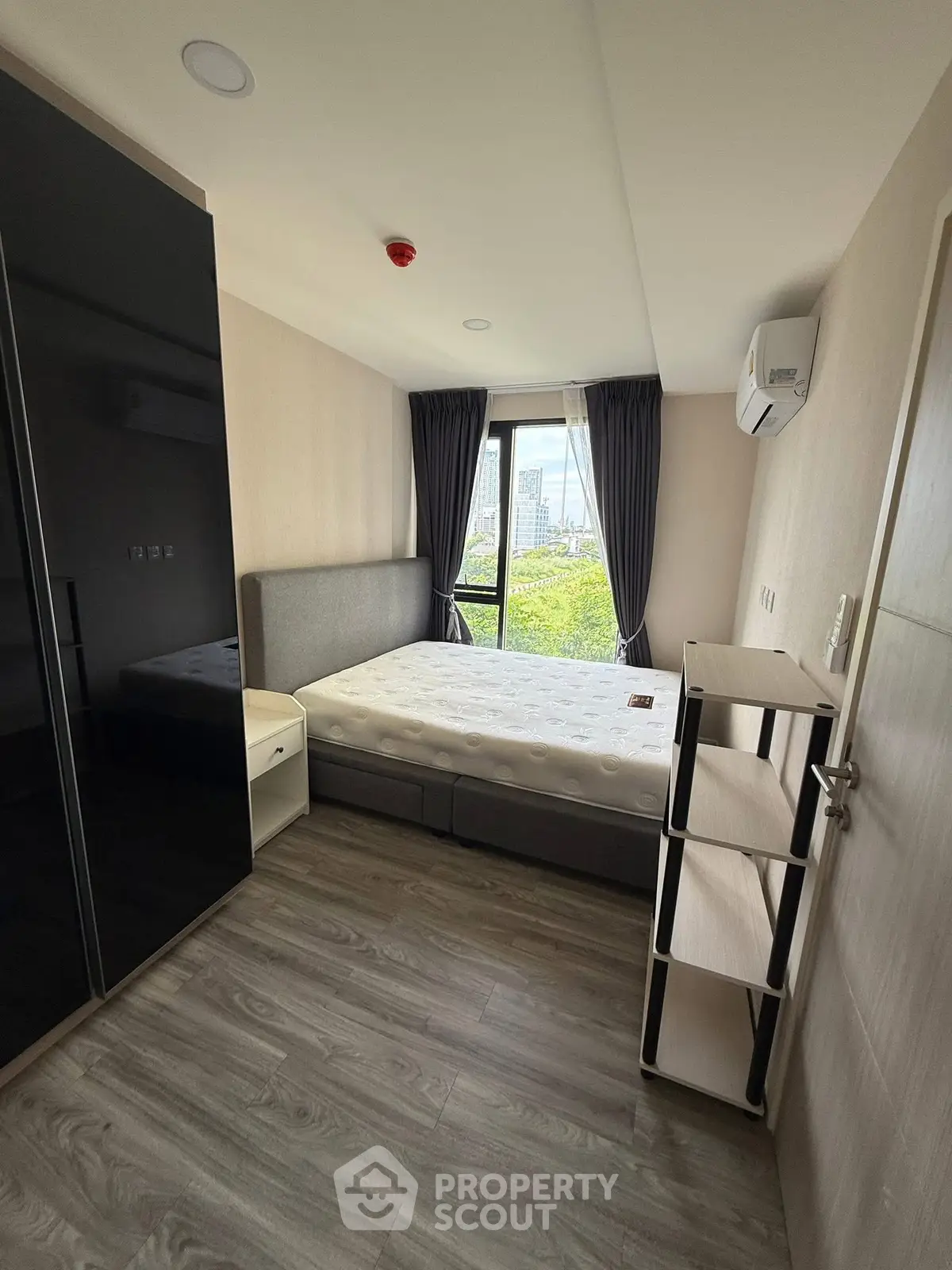 Modern bedroom with city view, sleek furniture, and ample natural light.