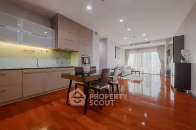 Spacious open-plan living room with modern kitchen and elegant dining area, featuring polished wooden floors and ample natural light.