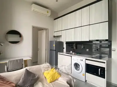Modern kitchen with integrated appliances and cozy living area in a stylish apartment.