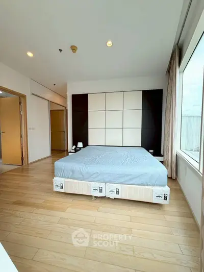Spacious bedroom with large windows and modern design in a luxury apartment.