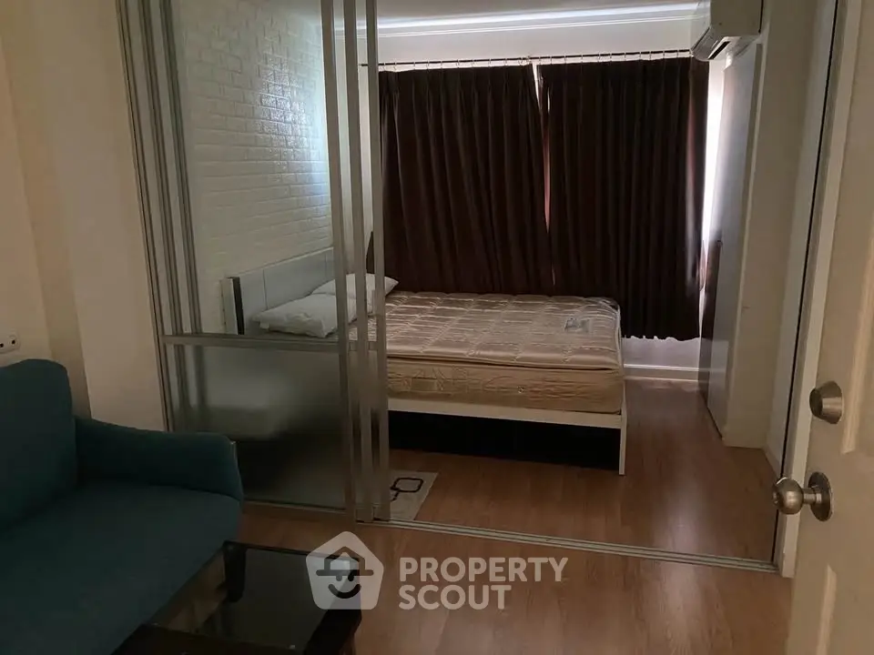 Cozy bedroom with sliding glass doors and wooden flooring in modern apartment.