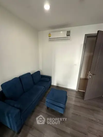 Cozy living room with blue sofa and air conditioning, perfect for relaxation.