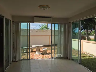 Spacious living room with large windows opening to a charming garden patio