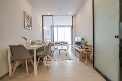 Modern living room with dining area and natural light, featuring stylish furniture and decor.