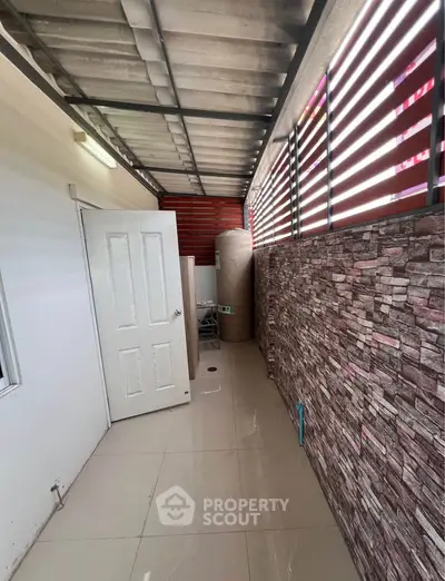 Covered outdoor area with tiled floor and stone accent wall, ideal for storage or utility use.