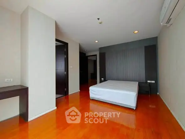 Spacious bedroom with wooden flooring and modern design in a luxury apartment.