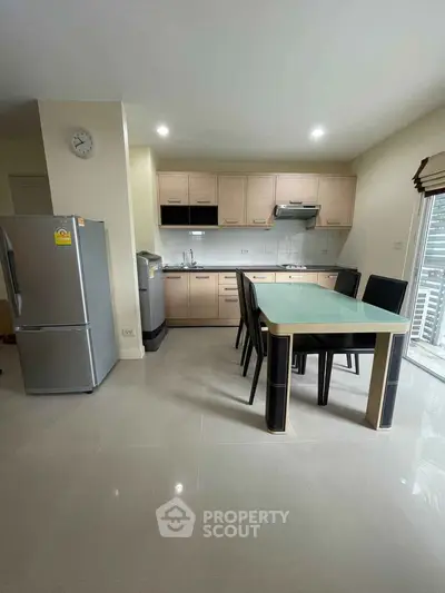 Modern kitchen with dining area, featuring sleek cabinetry and stainless steel appliances.