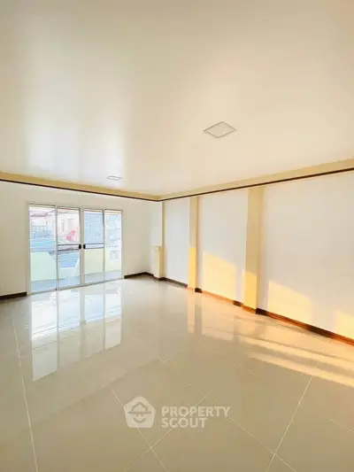 Spacious sunlit room with large windows and glossy tiled flooring, perfect for modern living.