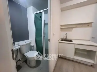 Compact bathroom with shower and adjacent kitchenette in modern apartment.