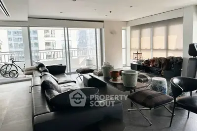 Spacious modern living room with sleek furniture and large windows offering city views.