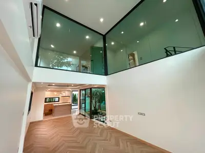 Stunning modern living room with high ceilings and glass walls, featuring elegant wood flooring and open layout.