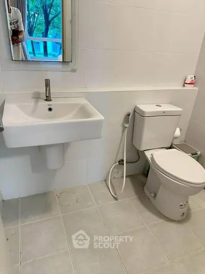 Modern bathroom with sleek white fixtures and tiled walls, offering a clean and minimalist design.