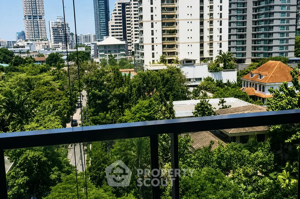 Stunning urban view from a balcony overlooking lush greenery and modern high-rise buildings.