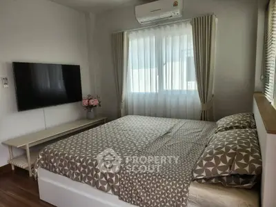 Cozy bedroom with modern decor and wall-mounted TV, perfect for relaxation.