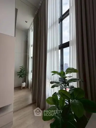 Luxurious high-ceiling interior with large windows and elegant curtains, offering a serene view.