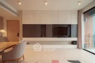 Modern living room with sleek built-in entertainment unit and open balcony access.