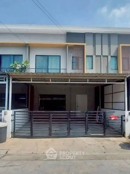 Modern townhouse exterior with gated entrance and balcony.