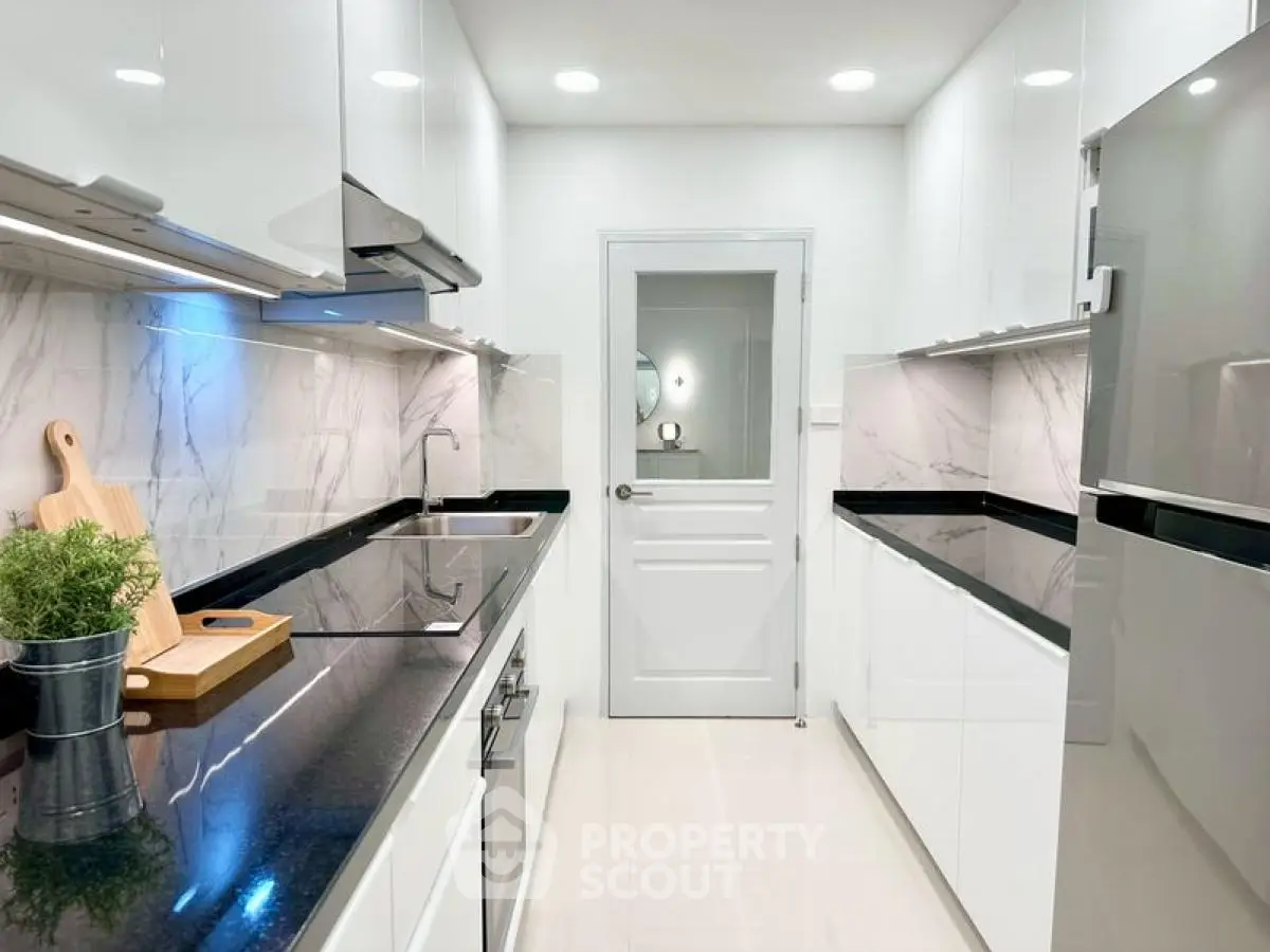 Sleek modern kitchen with glossy white cabinets and black countertops in a stylish apartment.