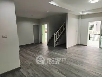 Spacious modern living room with sleek flooring and staircase, perfect for contemporary living.