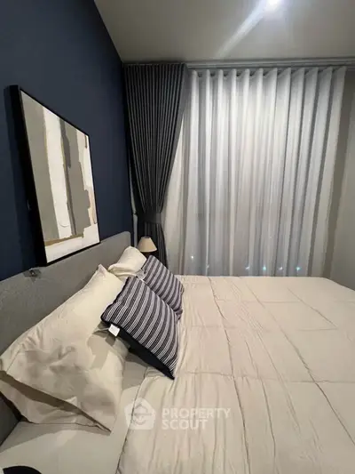 Modern bedroom with stylish decor and cozy ambiance, featuring elegant curtains and contemporary artwork.