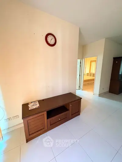 Spacious living room with wooden furniture and wall clock, ideal for cozy gatherings.