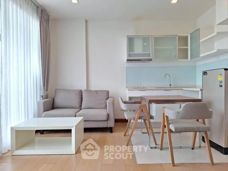 Modern open-layout living room with kitchen, featuring stylish furniture and natural light.