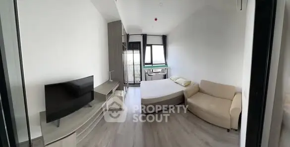 Modern bedroom with sleek design, featuring a cozy bed, stylish sofa, and flat-screen TV, perfect for urban living.