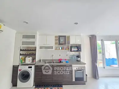 Modern kitchen with appliances and natural light, featuring sleek cabinetry and a washing machine.