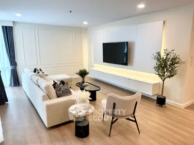 Spacious modern living room with elegant decor and large TV, perfect for relaxation.