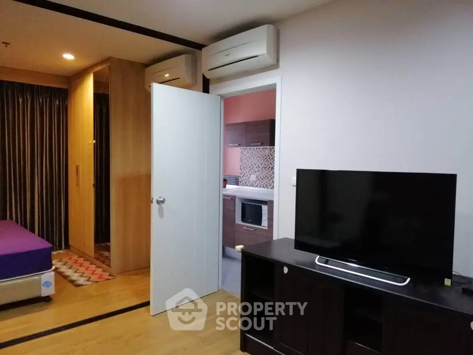 Modern apartment interior with TV and air conditioning, open view to kitchen