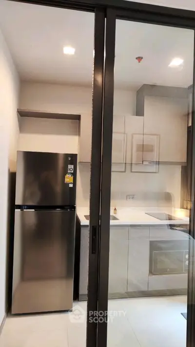 Modern kitchen with sleek appliances and minimalist design, featuring a stainless steel fridge and built-in oven.