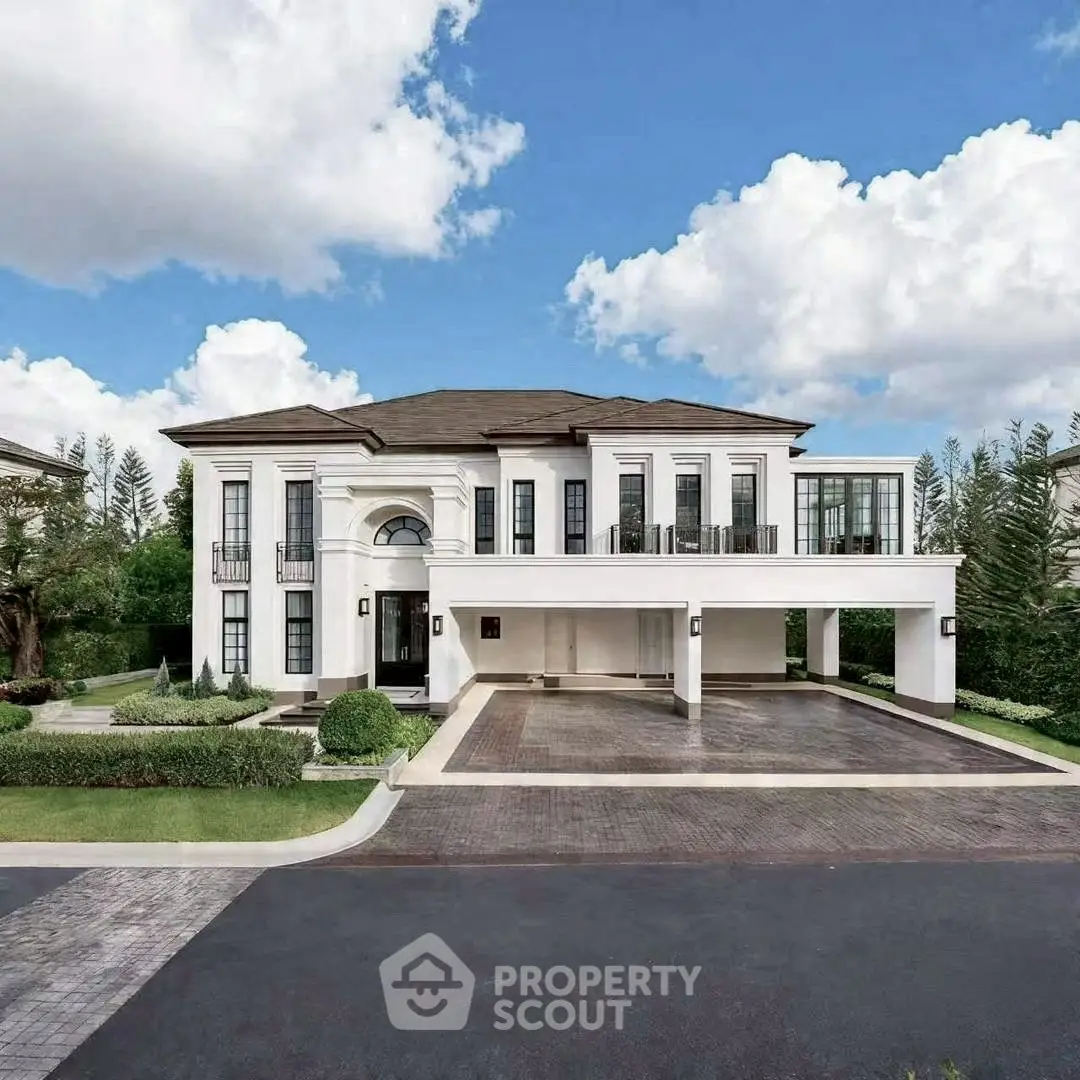 Luxurious modern mansion with grand entrance and spacious driveway, surrounded by lush greenery and clear blue sky.