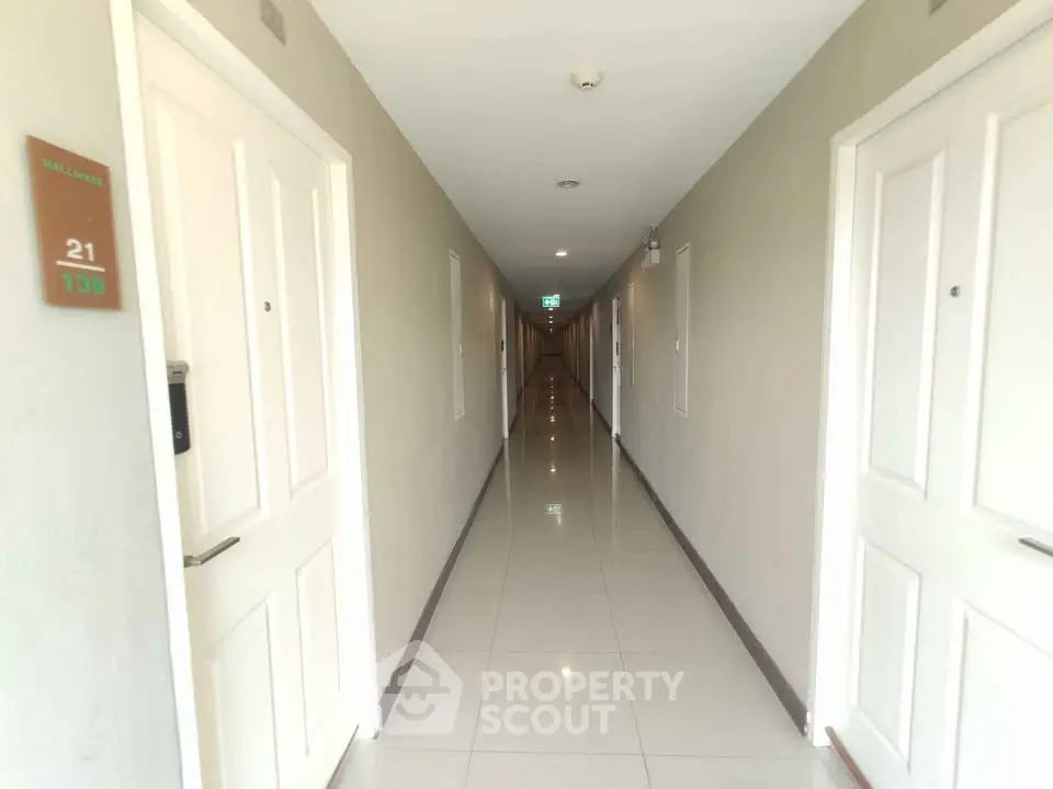 Bright and spacious hallway in modern apartment building with white doors and polished floors.