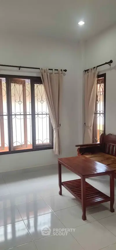 Bright living room with large windows and elegant wooden furniture, perfect for relaxation.